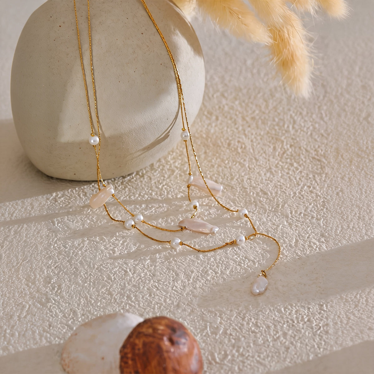 Belle Baroque Pearl Necklace styled on cream plaster with dried pampas