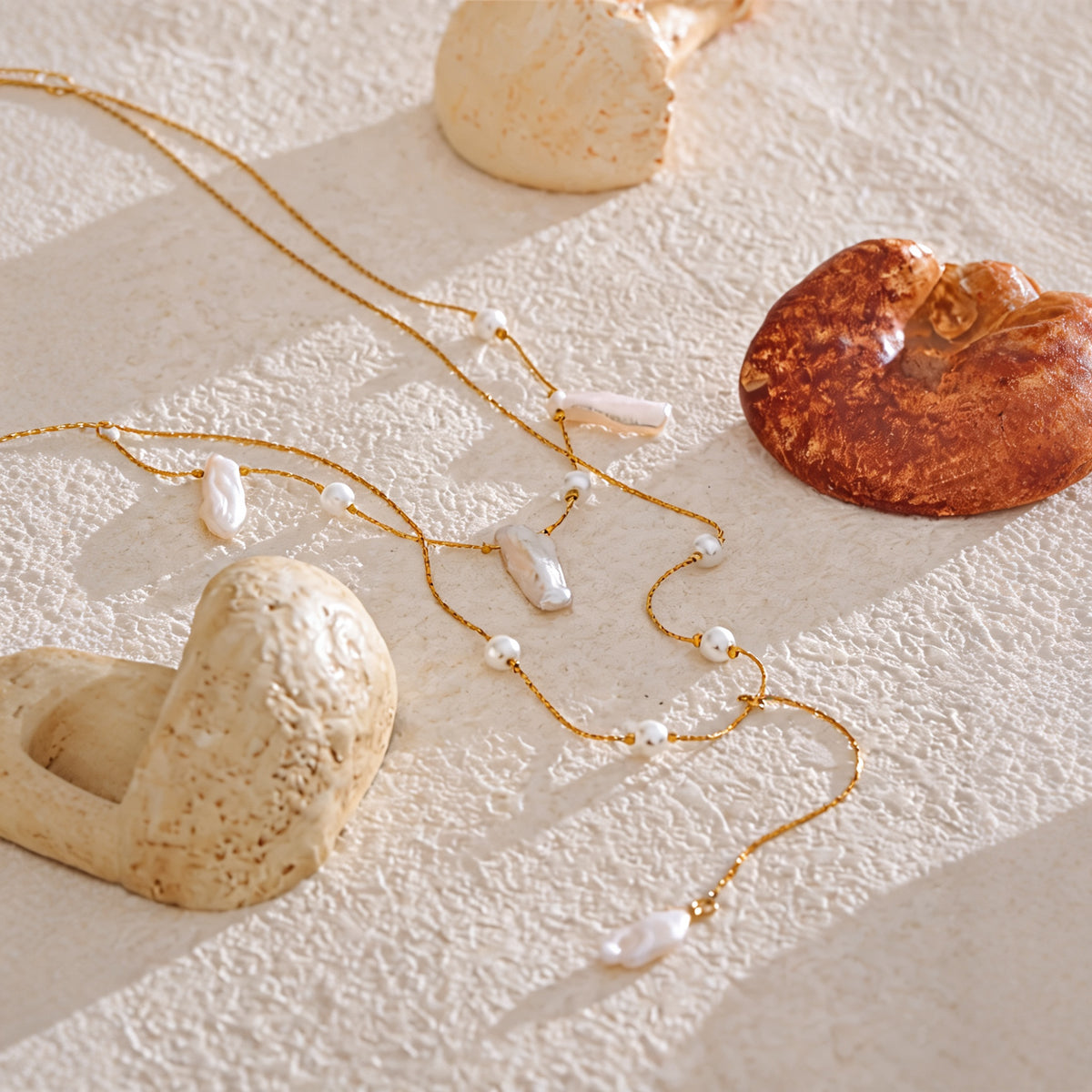 Belle Baroque Pearl Necklace laid on cream plaster in warm sunlight