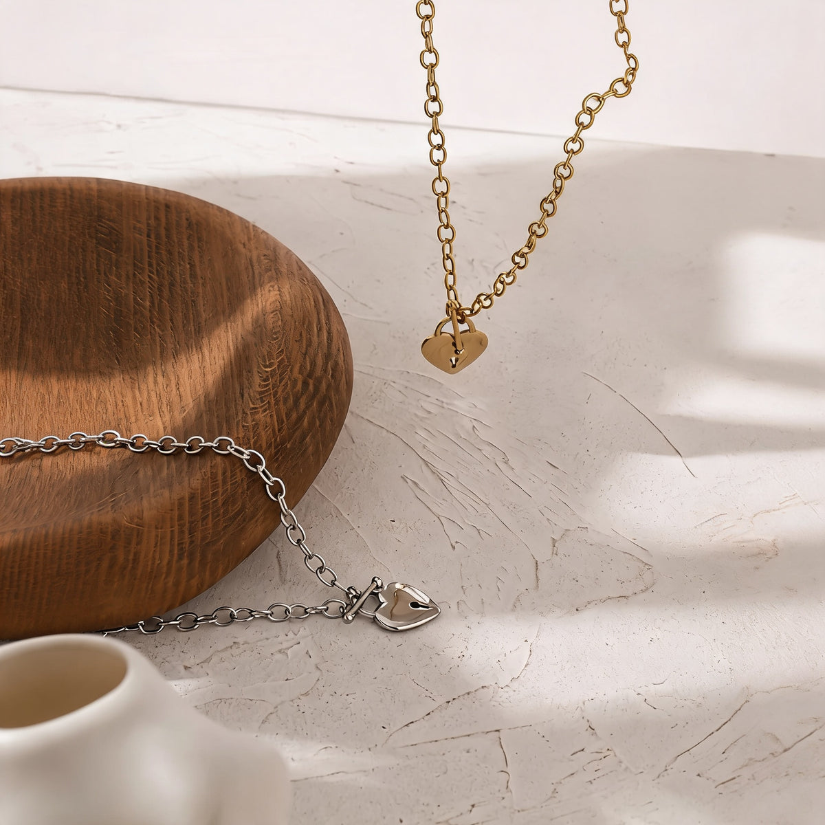 Etta heart lock choker in gold and silver styled on a plaster surface