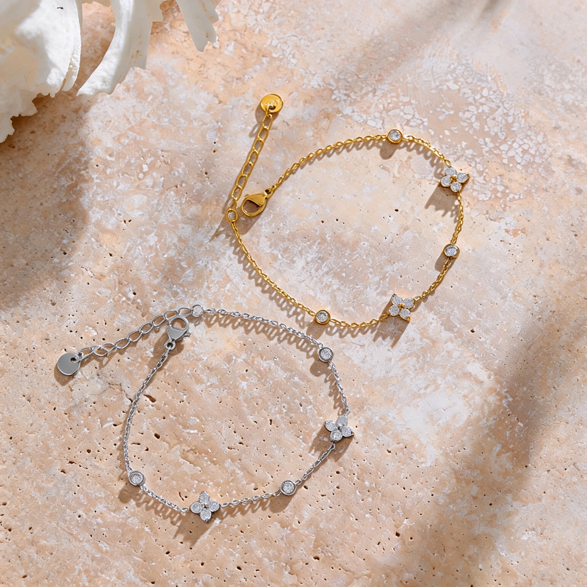 Flora zirconia flower bracelet in gold and silver on a travertine surface
