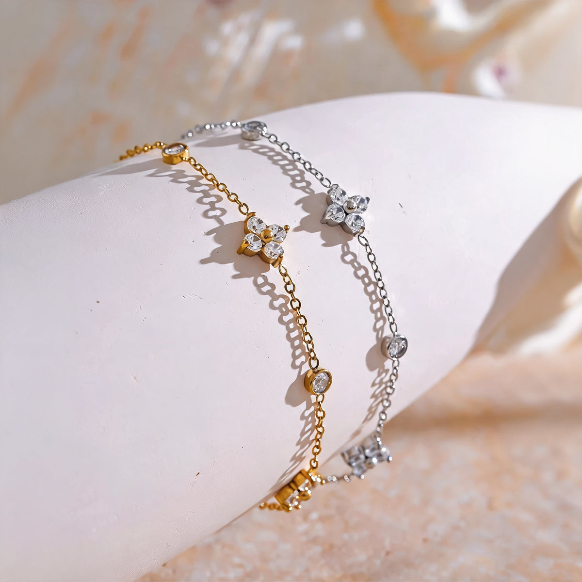 Gold and silver Flora zirconia flower bracelets draped over a ceramic form