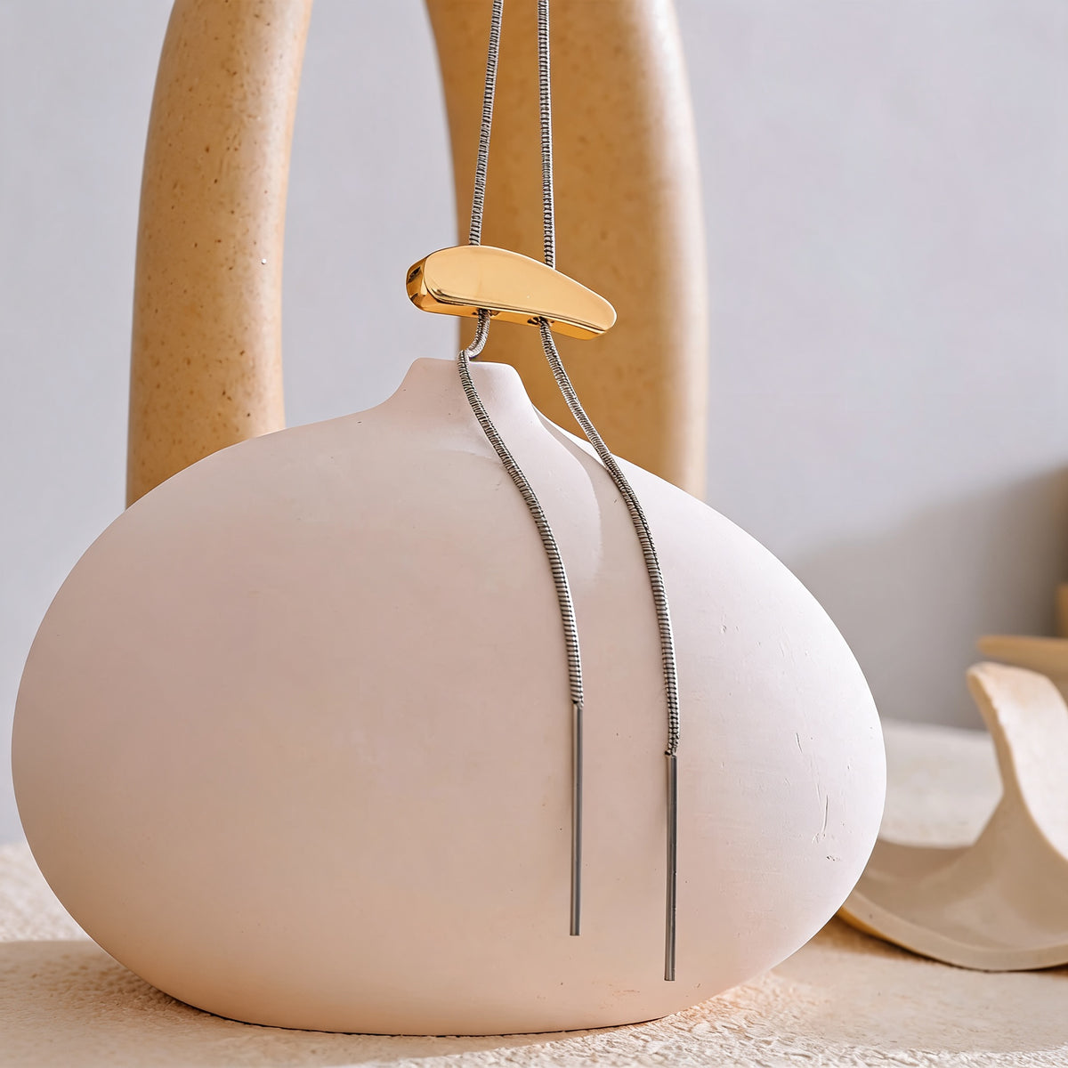 Marlow Long Chain Necklace draped over a cream ceramic vase