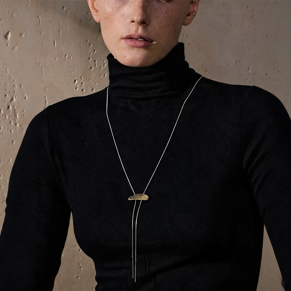 Marlow Long Chain Necklace worn over a black turtleneck, gold bar pendant with silver chain drop