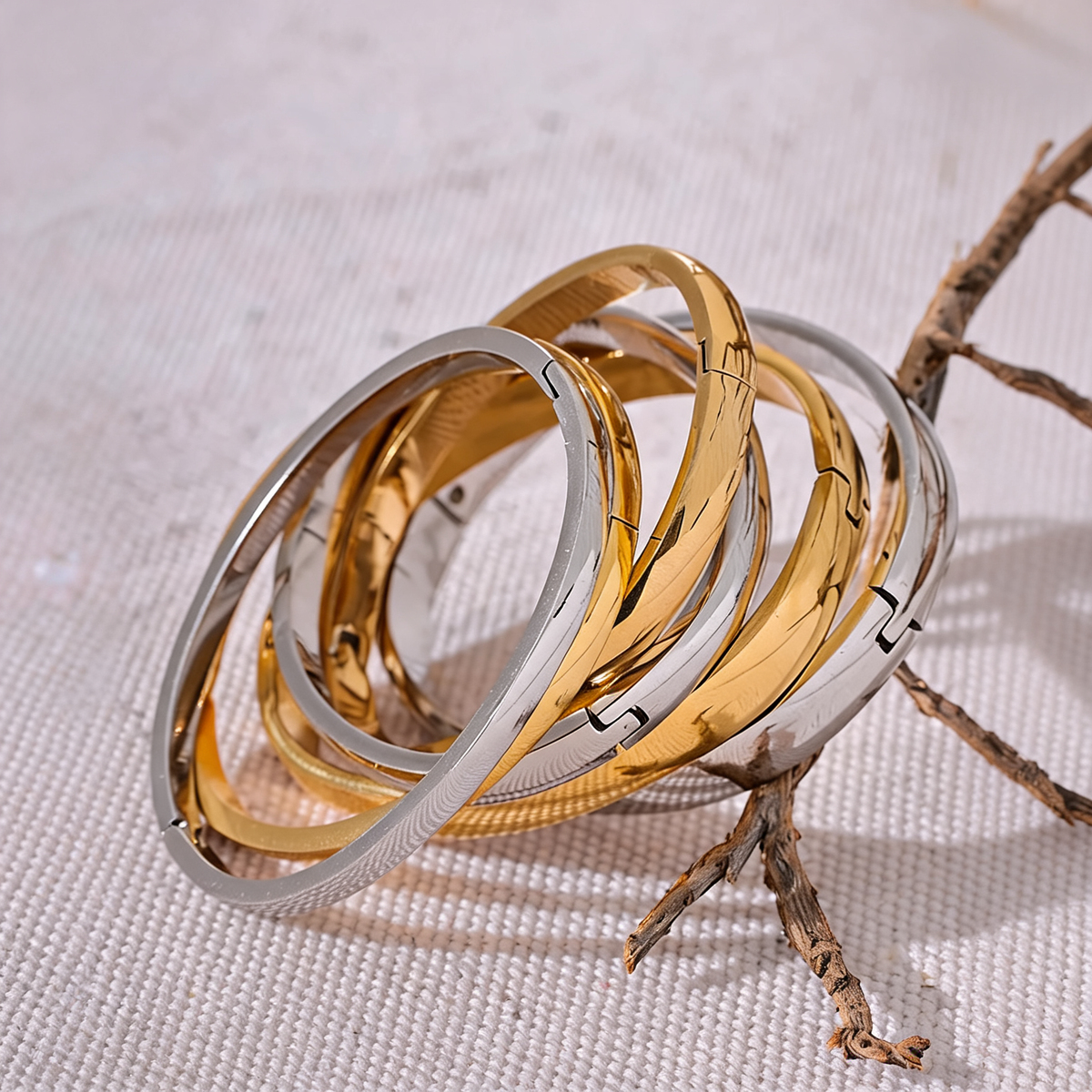 Gold and silver Rowan smooth bangles fanned across natural linen