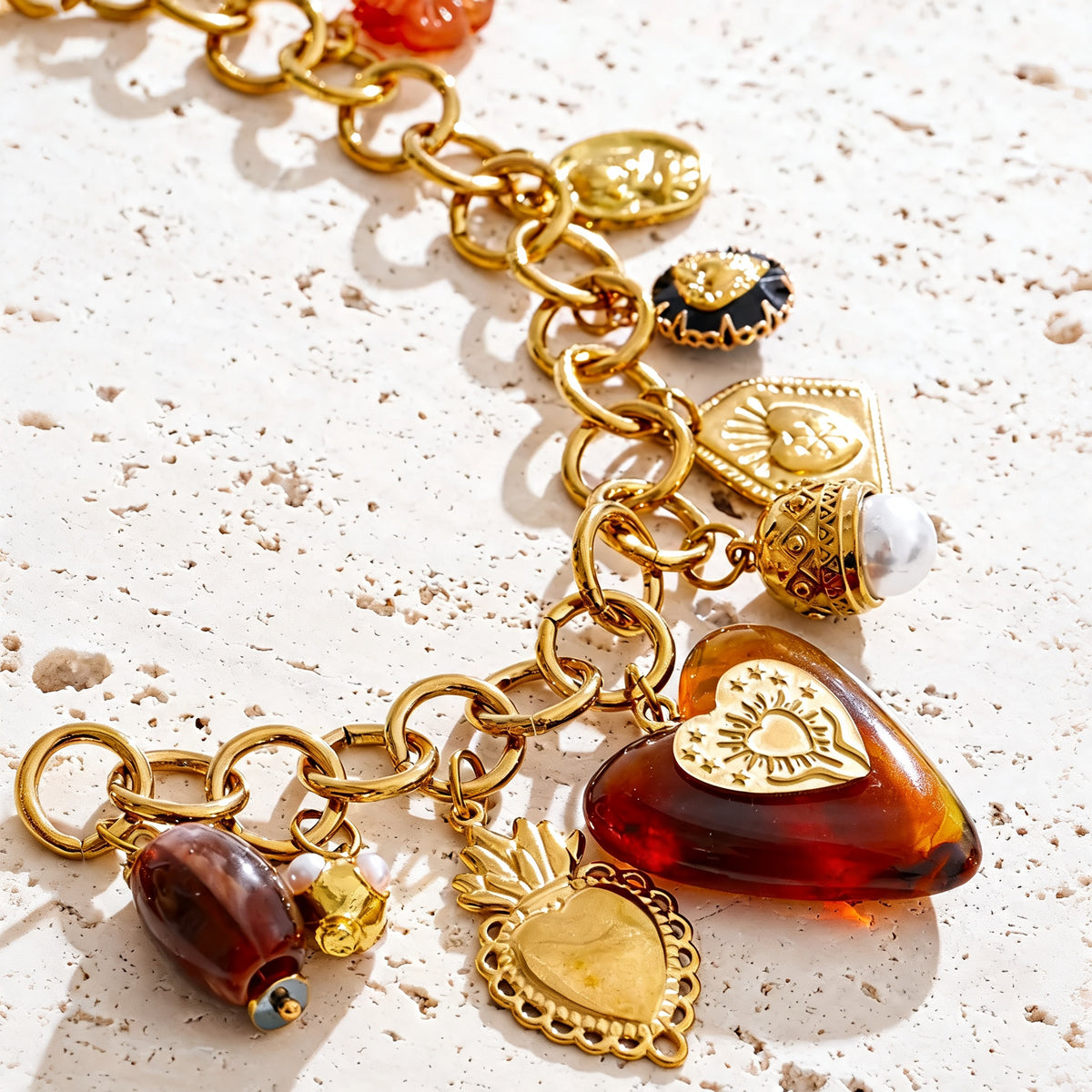 Close detail of the Ramona necklace charm cluster and amber-toned heart
