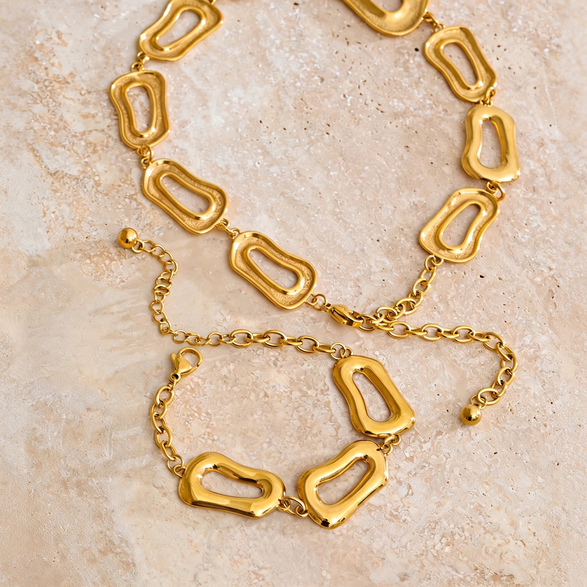 Harlow gold chain link necklace and bracelet set on a stone surface