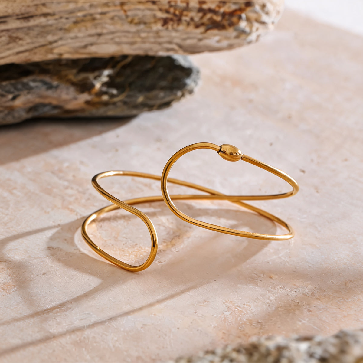 June Hollow Bangle in gold on a travertine surface
