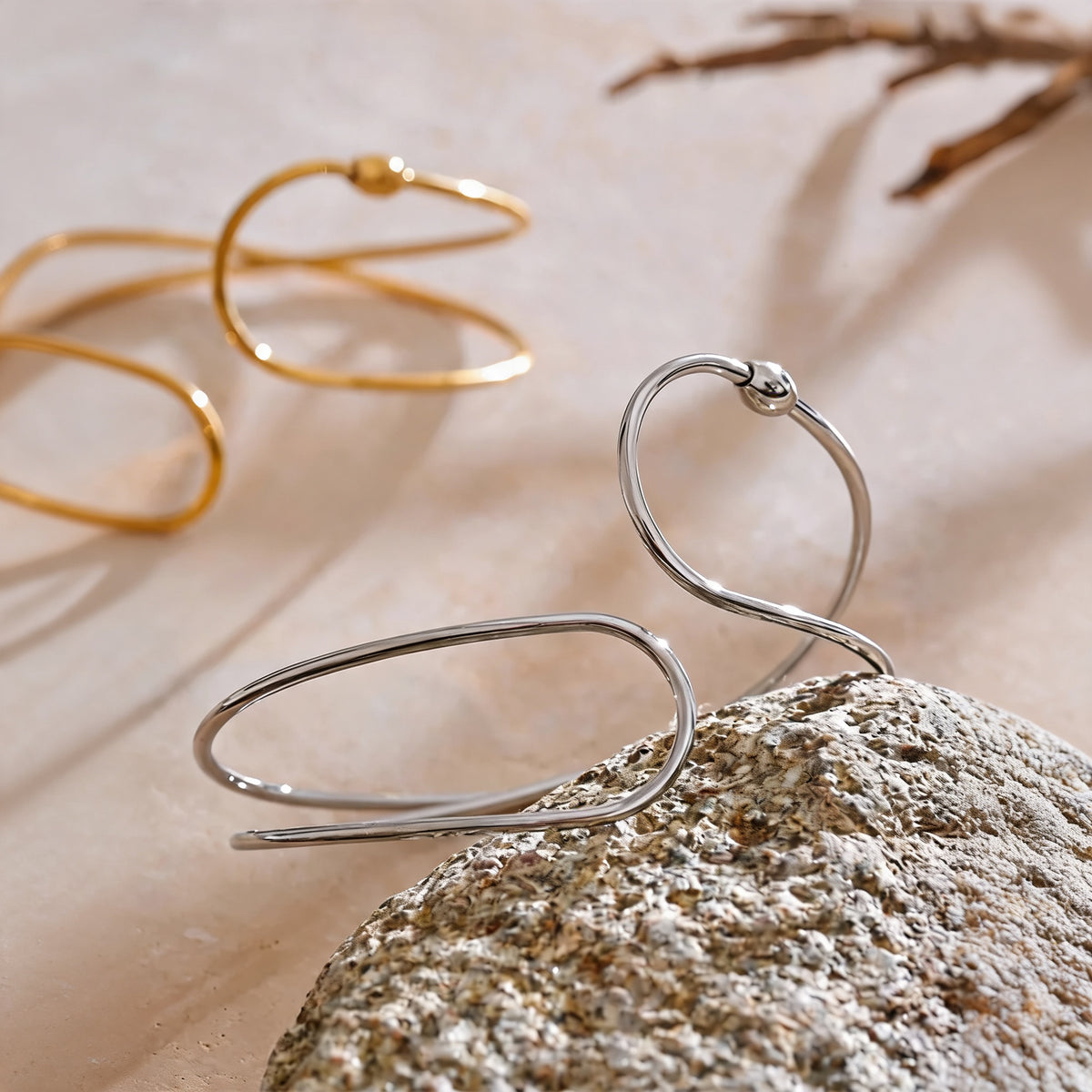June Hollow Bangle in silver resting against stone