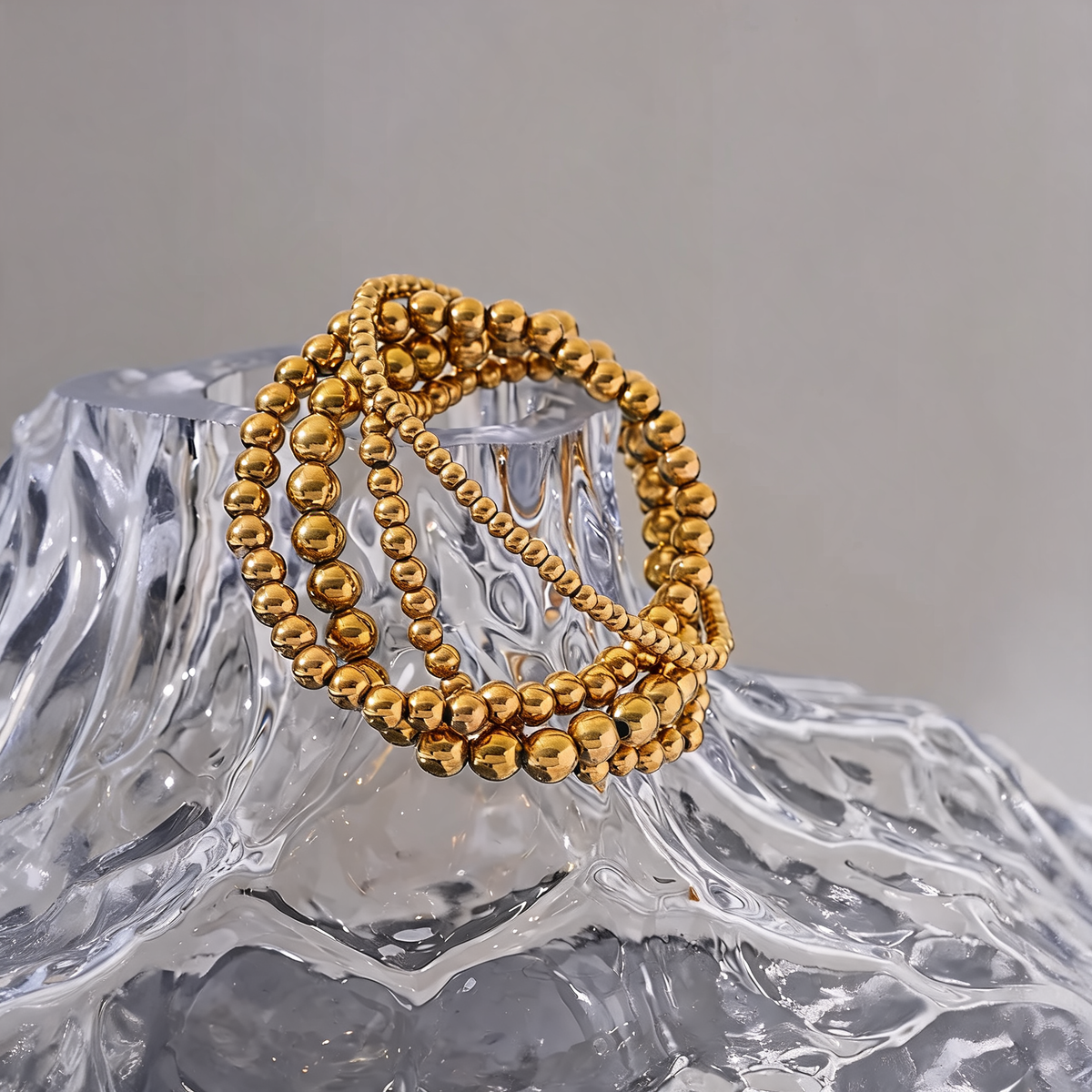 Gold beaded stretch bracelets stacked on a glass vessel