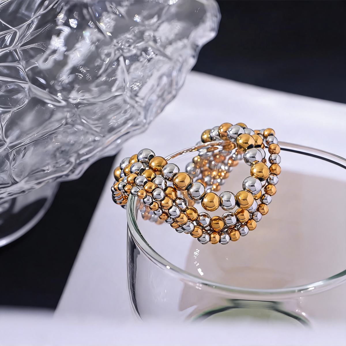 Two-tone gold and silver beaded stretch bracelets on a glass tumbler