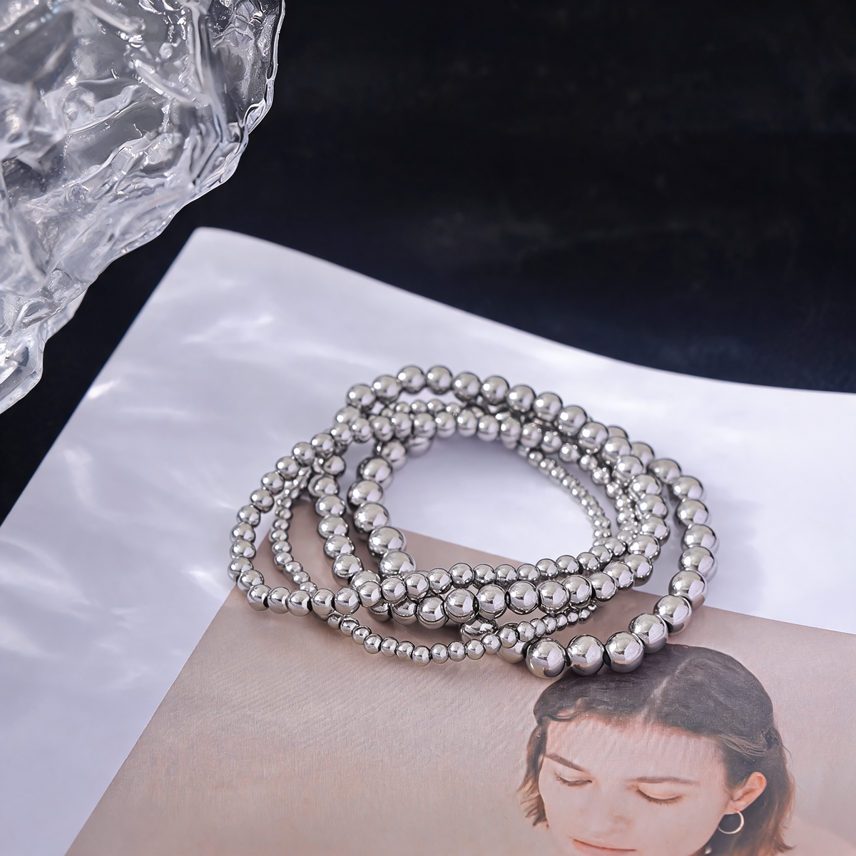 Silver beaded stretch bracelets on a white paper surface