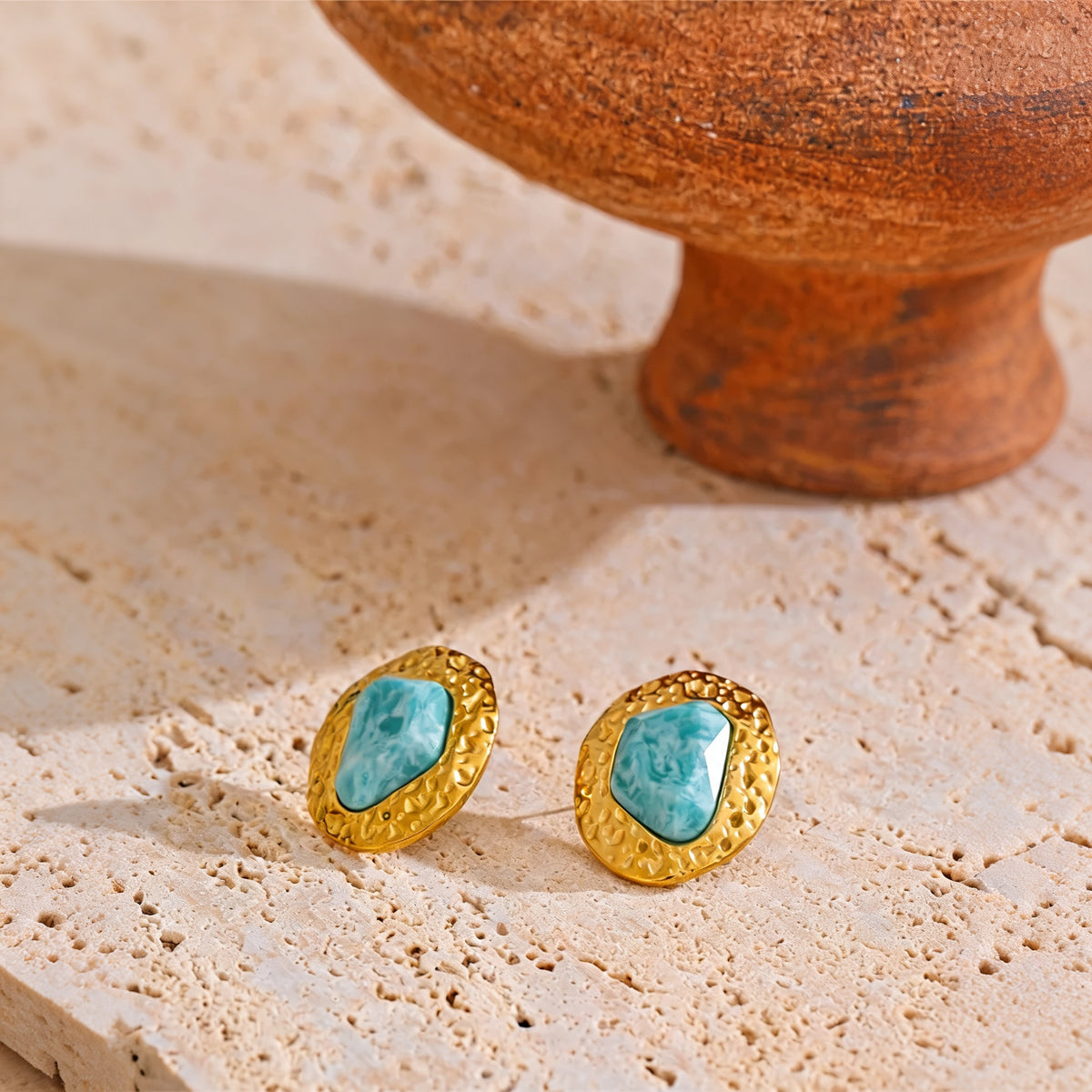 Lottie amazonite stud earrings resting on travertine beside a terracotta pedestal