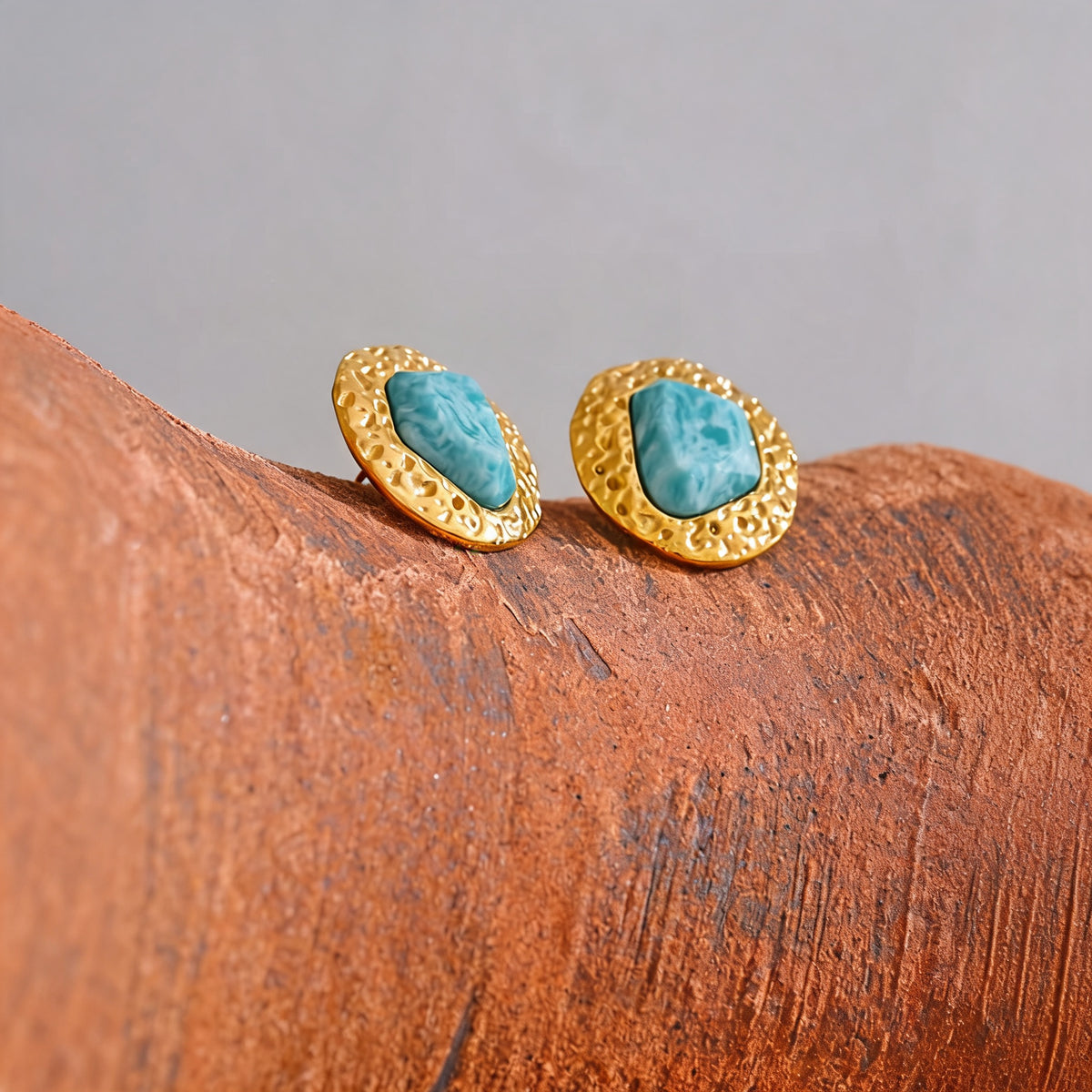 Lottie amazonite stud earrings perched on a terracotta edge against a soft grey backdrop
