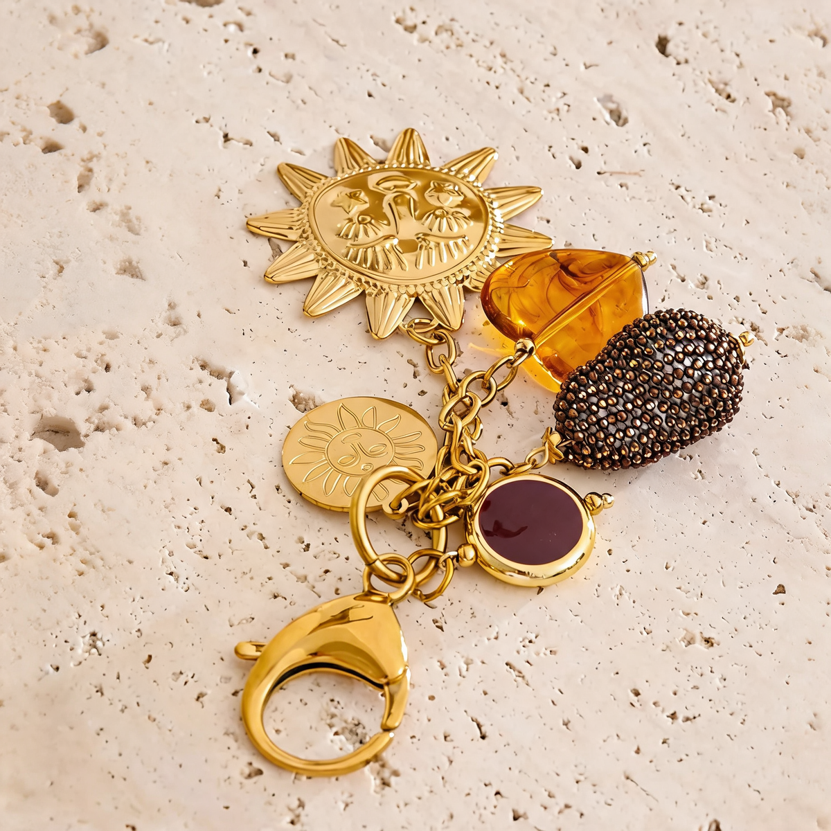 Marigold sun charm keychain with all five charms spread on travertine