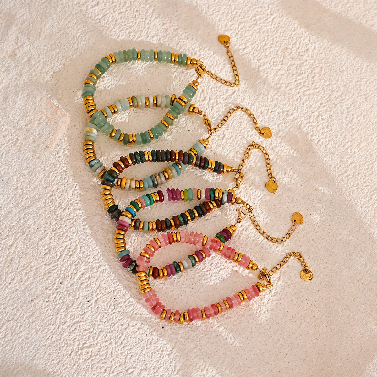Five Sedona Stone Bead Bangle colorways fanned on a warm sand surface