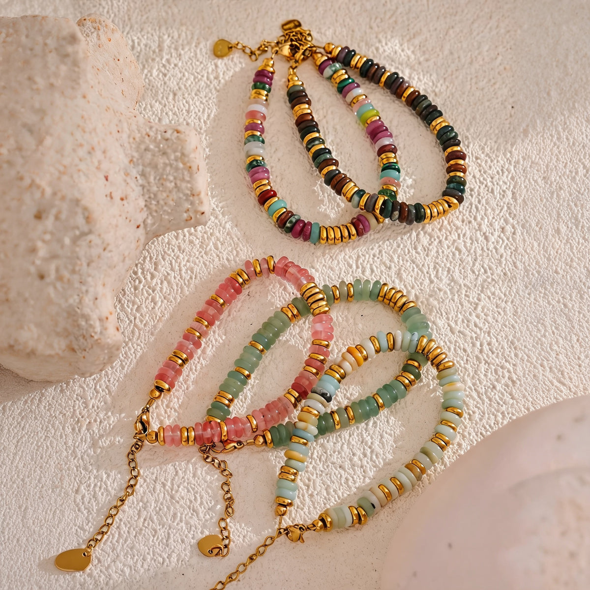 Four Sedona Stone Bead Bangle colorways laid on cream textured stone