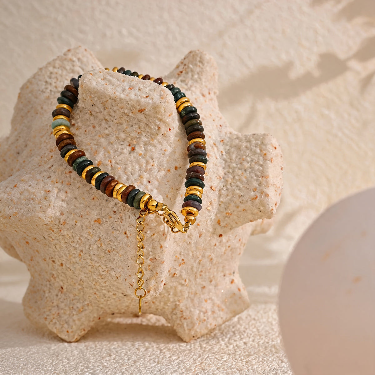 Sedona Stone Bead Bangle draped over a cream coral sculpture in warm light