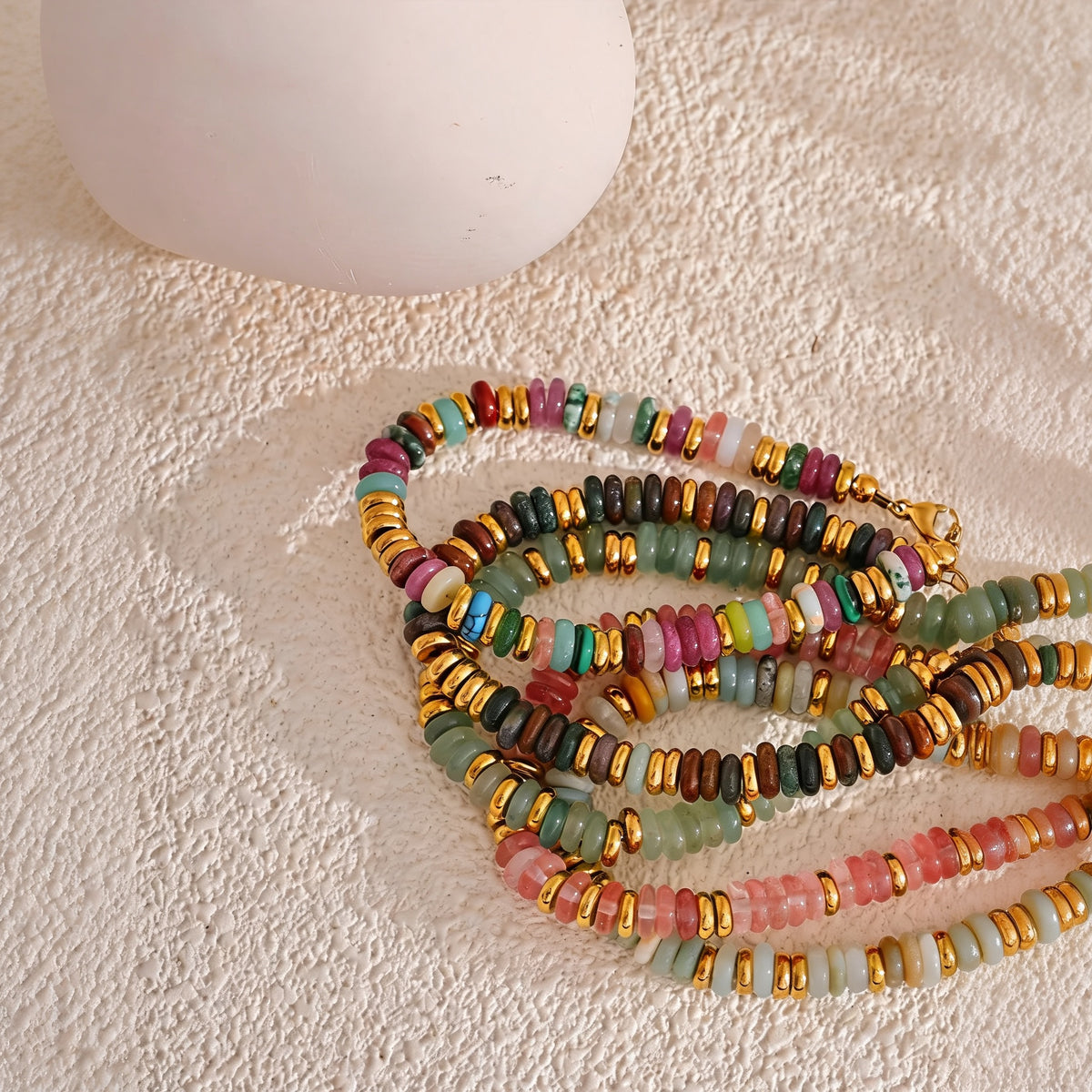 Stack of Sedona Stone Bead Bangle colorways coiled on cream texture